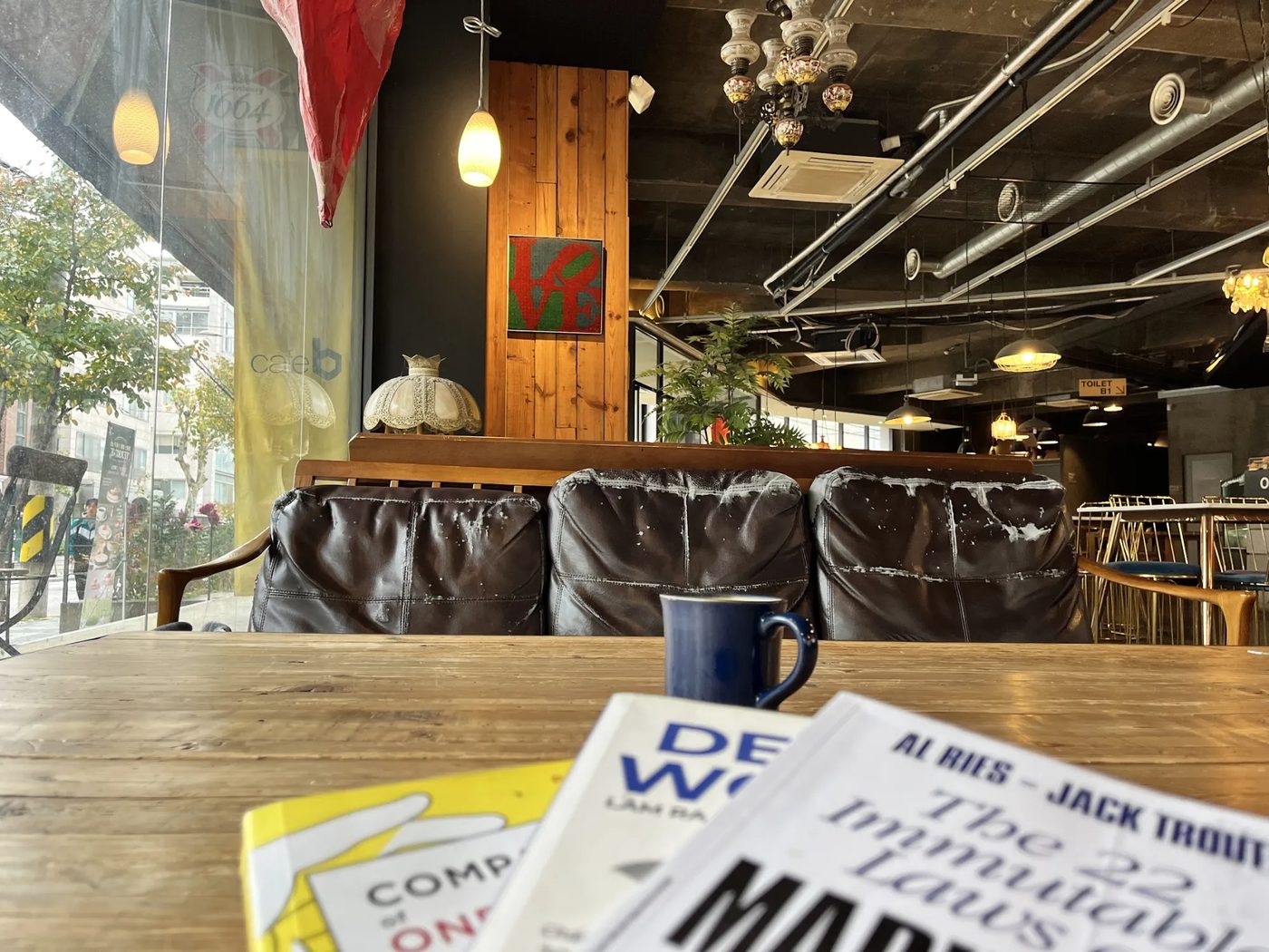 Góc quán cà phê quen ở Seoul với ghế sofa da cũ, đèn, và vài cuốn sách trên bàn